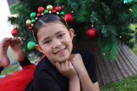 Seven year-old Eseta Tuisuva from Warrnambool enjoys the carols from underneath the tree.