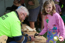 Seven year-old Winnie Oates makes a timber plane with help from members of the Men’s Shed.