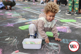 Three year-old Carmelo Williams, of Warrnambool, adds his creative talents to the street with some coloured chalk.